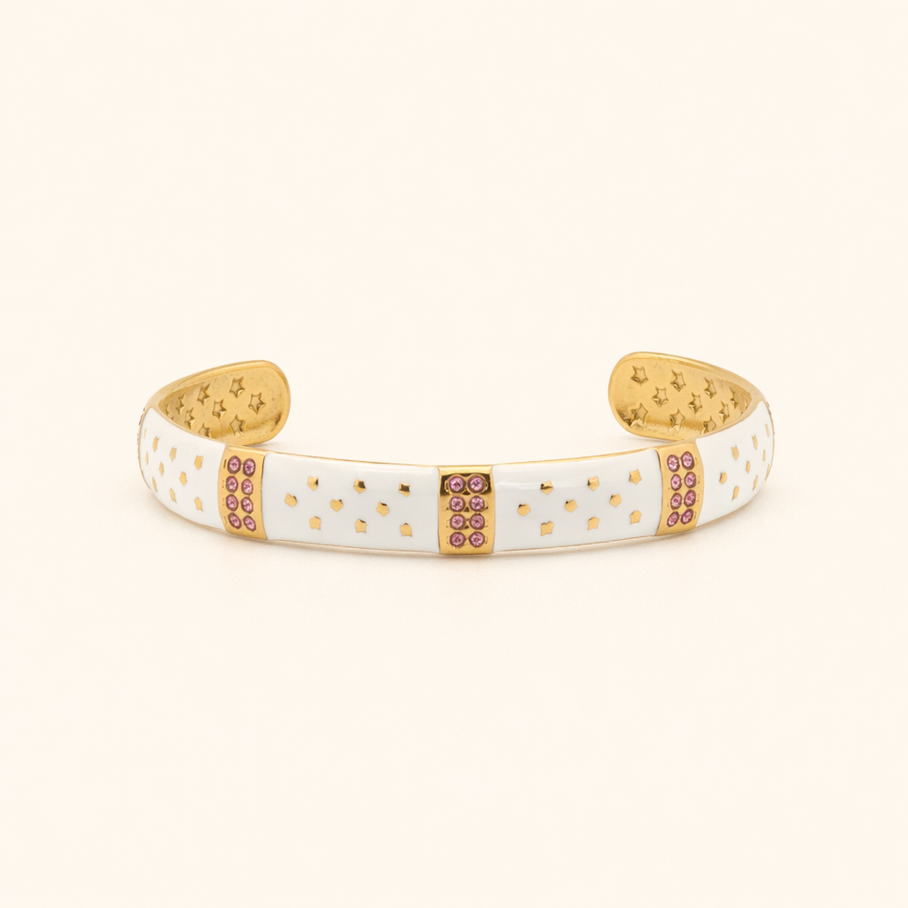 White cuff bracelet with gold accents and pink stones on a beige background